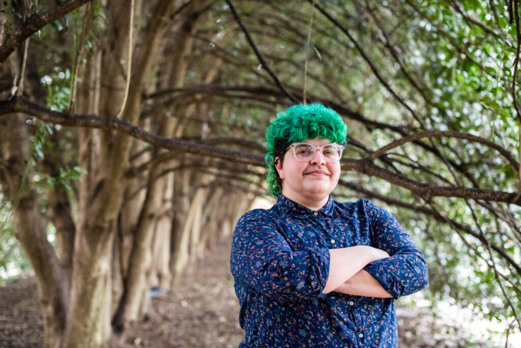 Jaq Payne standing in front of grove of trees - Photo Credit: Aw Snap Photography