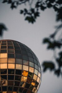 The Sunsphere against a gray sky with leaves in foreground